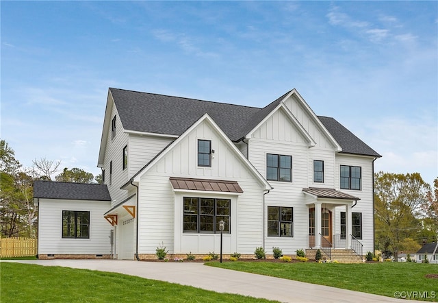 modern farmhouse with board and batten siding, fence, driveway, roof with shingles, and a front lawn
