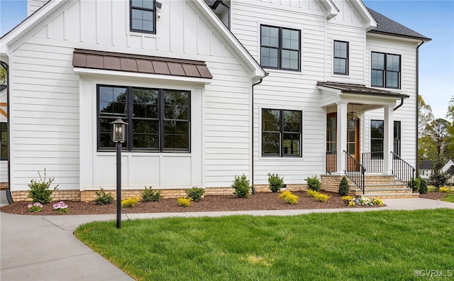 modern farmhouse with a standing seam roof, board and batten siding, and a front yard