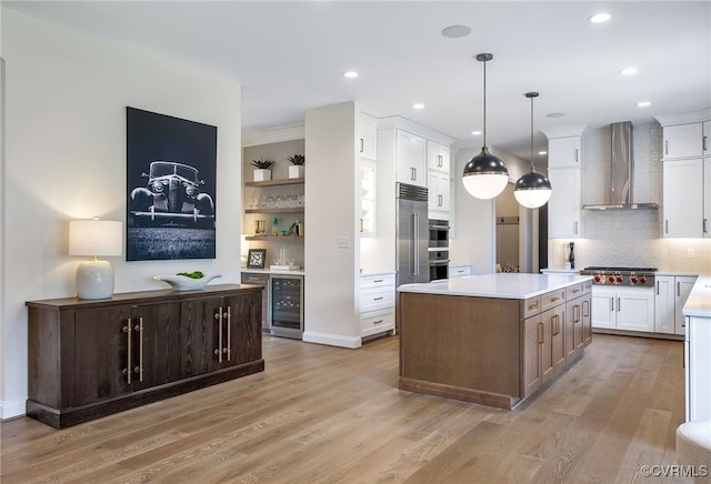 kitchen featuring beverage cooler, stainless steel gas cooktop, wall chimney range hood, backsplash, and light wood finished floors