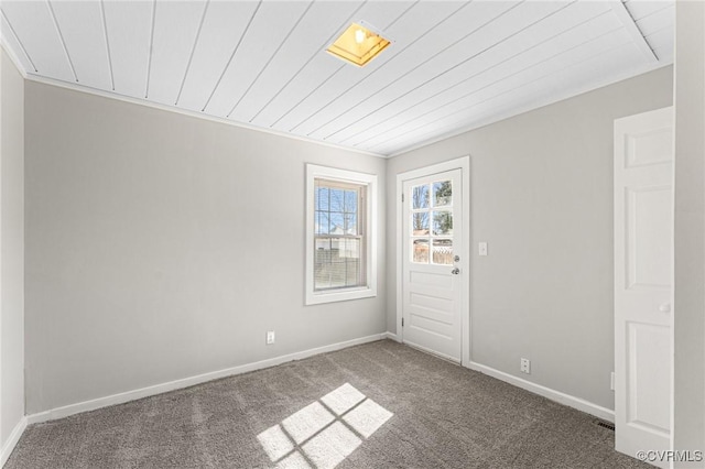 empty room featuring baseboards, wooden ceiling, and carpet flooring