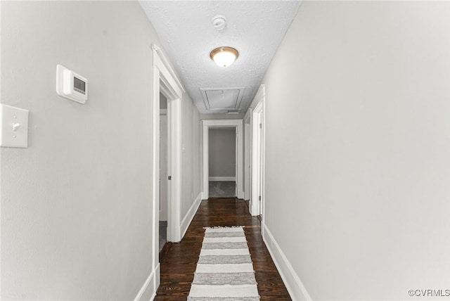 hallway featuring baseboards, dark wood-style flooring, and a textured ceiling