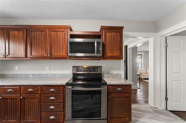 kitchen featuring a textured ceiling, wood finished floors, and stainless steel appliances