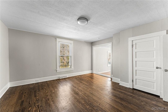 unfurnished room featuring baseboards, visible vents, wood finished floors, and a textured ceiling