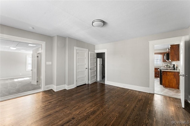 unfurnished living room featuring baseboards, a textured ceiling, and wood finished floors