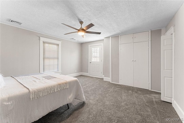 carpeted bedroom featuring baseboards, visible vents, a textured ceiling, and a ceiling fan
