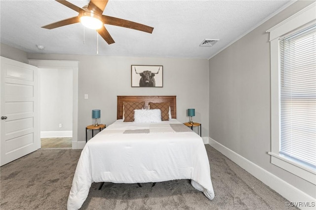carpeted bedroom with baseboards, a textured ceiling, visible vents, and a ceiling fan