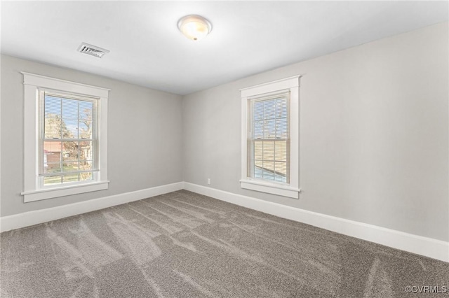 carpeted empty room featuring baseboards and visible vents