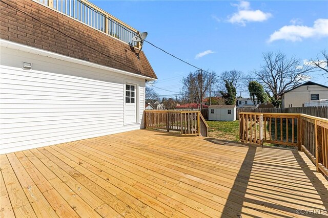 wooden deck with a shed, an outbuilding, and fence