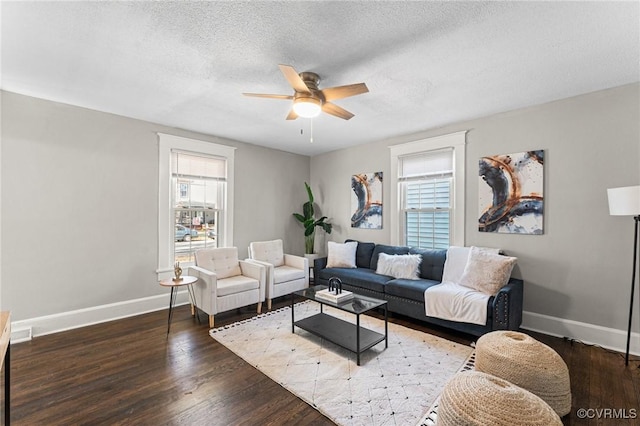 living room with a textured ceiling, baseboards, wood finished floors, and a ceiling fan