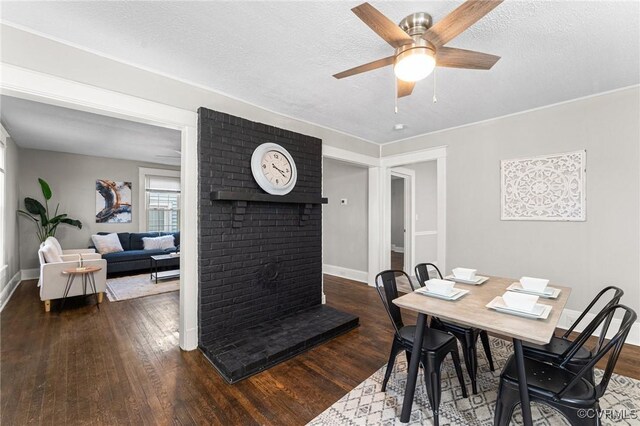 dining space with a textured ceiling, a fireplace, a ceiling fan, and hardwood / wood-style floors
