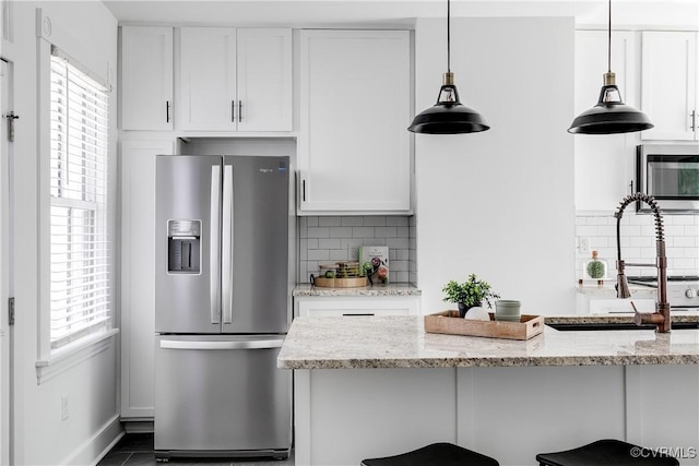 2205 Fairmount Ave, Richmond, VA 23223 - kitchen with a kitchen bar, tasteful backsplash, white cabinetry, appliances with stainless steel finishes, and hanging light fixtures