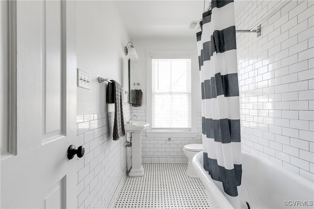 2205 Fairmount Ave, Richmond, VA 23223 - bathroom featuring tile walls, toilet, shower / tub combo, and a wainscoted wall