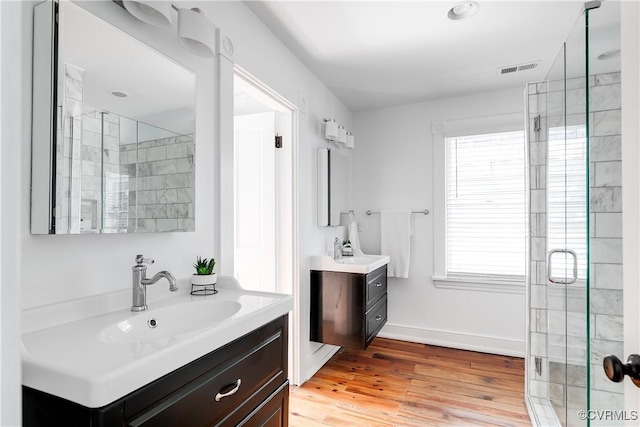 2205 Fairmount Ave, Richmond, VA 23223 - full bath featuring two vanities, a shower stall, visible vents, a sink, and wood finished floors