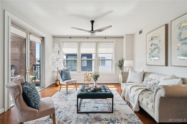 living area featuring baseboards, a ceiling fan, wood finished floors, and visible vents