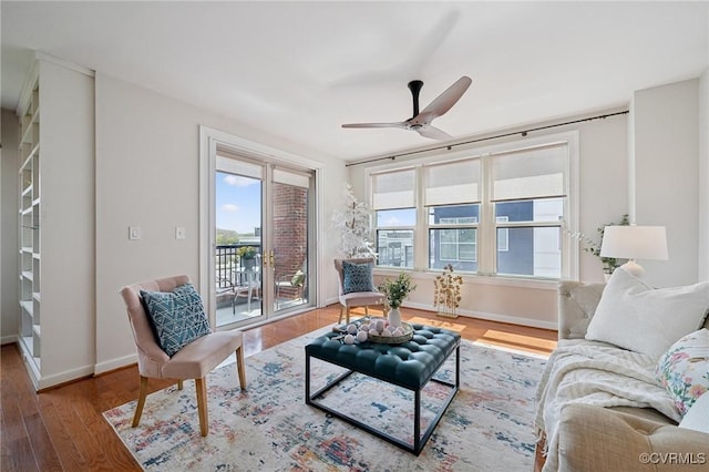 living area with baseboards, a ceiling fan, and wood finished floors