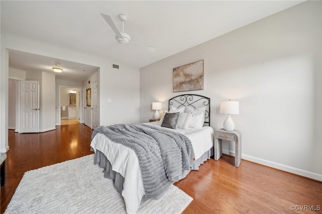 bedroom featuring visible vents, baseboards, ceiling fan, and wood finished floors