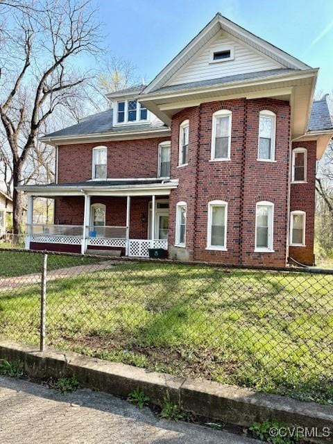 view of front facade featuring a front yard, a porch, fence, and brick siding