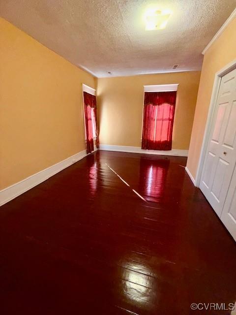 spare room featuring baseboards, a textured ceiling, and wood finished floors