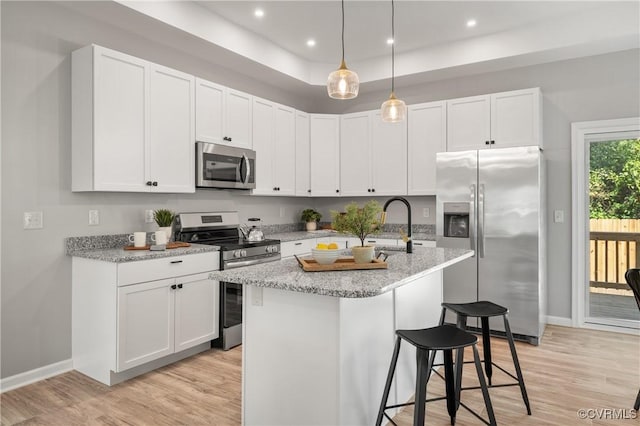 kitchen featuring light wood-style flooring, white cabinetry, a kitchen bar, and appliances with stainless steel finishes