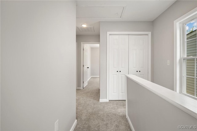 hall with carpet flooring, an upstairs landing, and baseboards