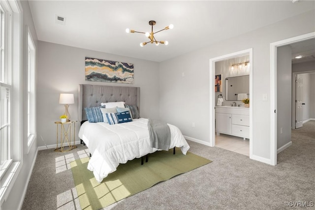 carpeted bedroom with a sink, ensuite bath, baseboards, visible vents, and an inviting chandelier