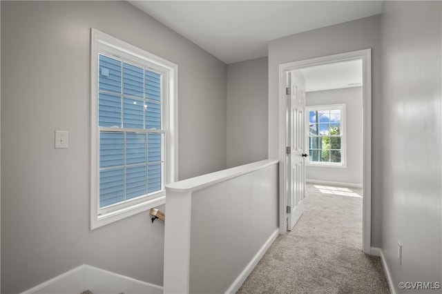 hallway featuring baseboards, carpet flooring, and an upstairs landing