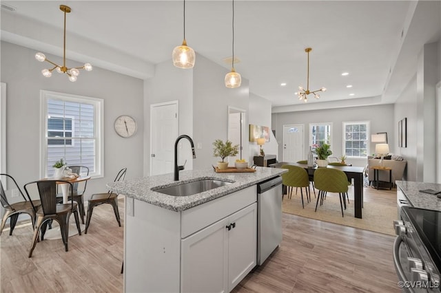kitchen featuring a notable chandelier, a sink, light wood finished floors, open floor plan, and stainless steel appliances