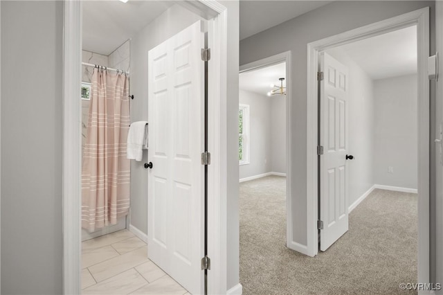 hall with baseboards and light carpet