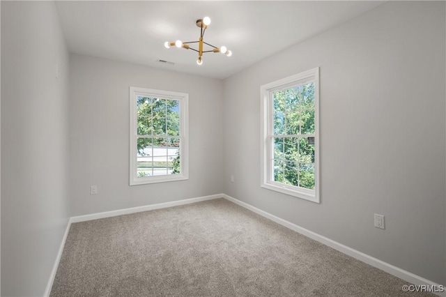unfurnished room with a wealth of natural light, baseboards, carpet flooring, and a chandelier