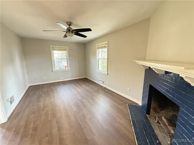 unfurnished living room with wood finished floors, ceiling fan, baseboards, and a brick fireplace