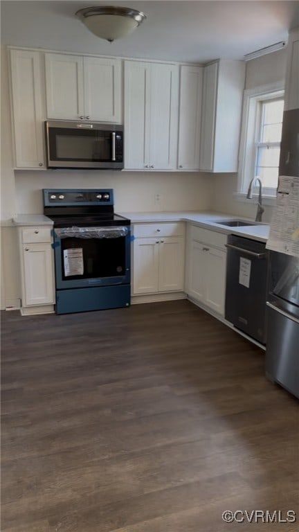 kitchen featuring stainless steel microwave, light countertops, a sink, dishwasher, and range with electric cooktop