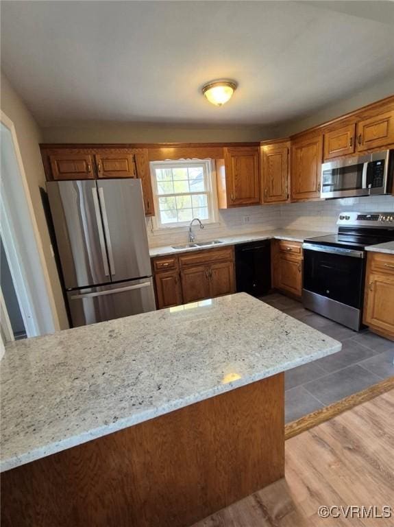 309 Royal Oak Ave, Colonial Heights, VA 23834 - kitchen with appliances with stainless steel finishes, backsplash, brown cabinetry, light stone counters, and wood finished floors