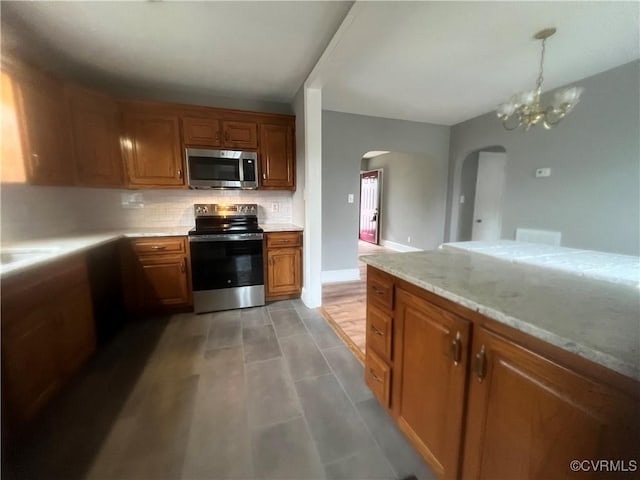 309 Royal Oak Ave, Colonial Heights, VA 23834 - kitchen with appliances with stainless steel finishes, arched walkways, backsplash, brown cabinetry, and a chandelier