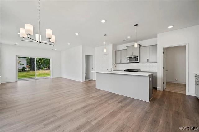 122 Steyland St, Ashland, VA 23005 - kitchen with stainless steel microwave, gray cabinetry, a chandelier, light countertops, and open floor plan