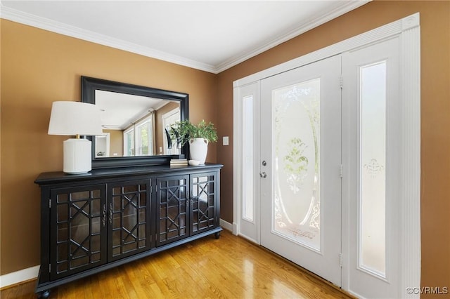 entryway with wood finished floors, baseboards, and crown molding