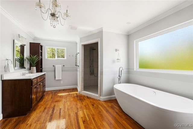 full bath featuring a shower stall, a freestanding bath, wood finished floors, vanity, and ornamental molding