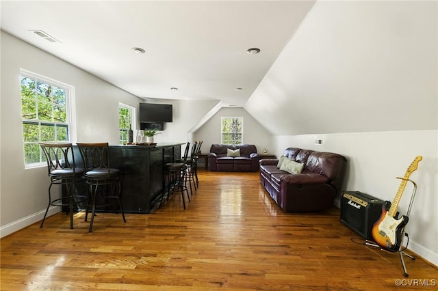living area featuring baseboards, wood finished floors, visible vents, and a dry bar