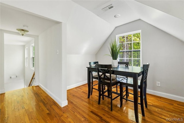 dining area featuring vaulted ceiling, wood finished floors, visible vents, and baseboards