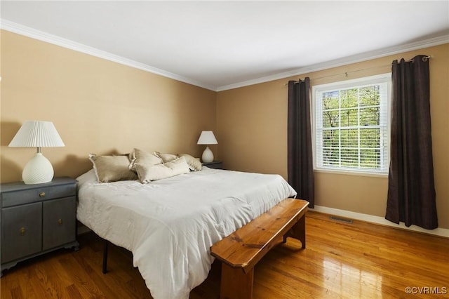 bedroom featuring visible vents, wood finished floors, baseboards, and crown molding