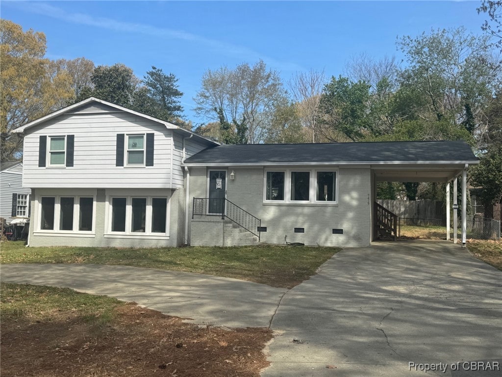 split level home with a shingled roof, driveway, a carport, and brick siding