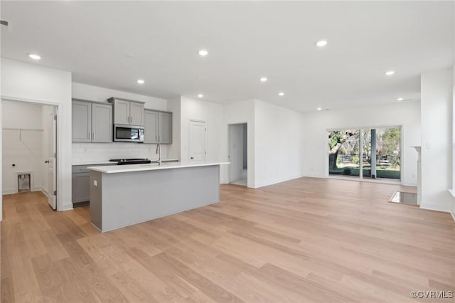 124 Steyland St, Ashland, VA 23005 - kitchen with stainless steel microwave, gray cabinets, a center island with sink, recessed lighting, and light wood-style floors