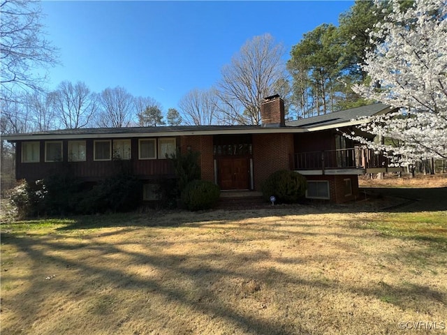 rear view of house featuring a chimney and brick siding