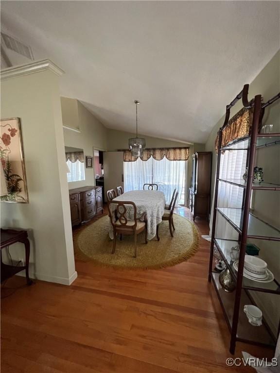 dining space with a chandelier, visible vents, wood finished floors, and lofted ceiling