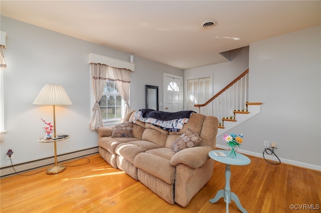 living area featuring baseboards, visible vents, stairway, and wood finished floors
