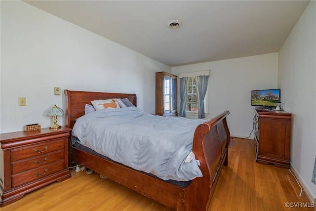 bedroom with light wood finished floors and visible vents