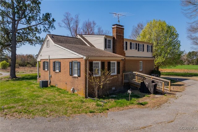 exterior space featuring crawl space, brick siding, central AC, a yard, and a chimney