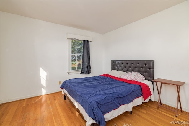 bedroom with wood-type flooring and baseboards