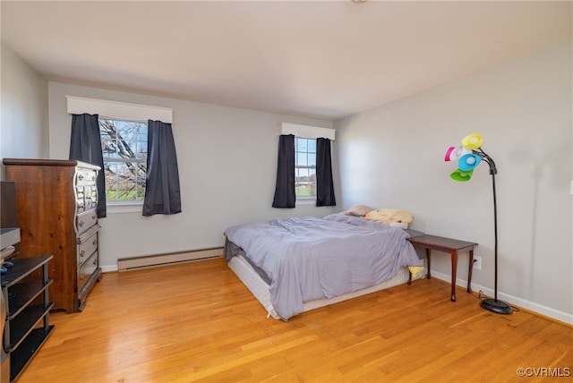 bedroom with baseboards, light wood finished floors, and baseboard heating