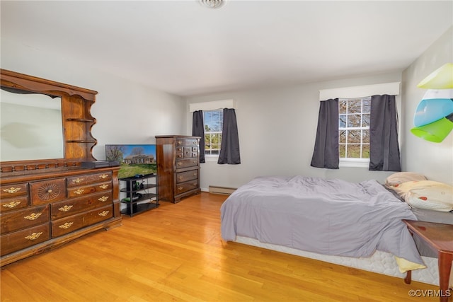bedroom featuring light wood-style flooring, multiple windows, and baseboard heating