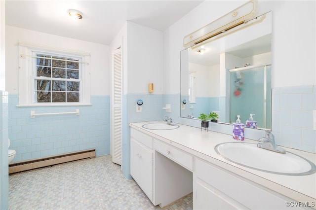 full bath featuring double vanity, a sink, a baseboard heating unit, and a stall shower